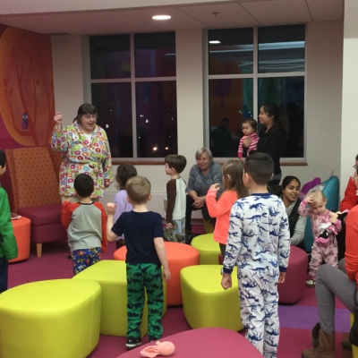 Families in Children's Room with Children's Librarian, some children in pajamas