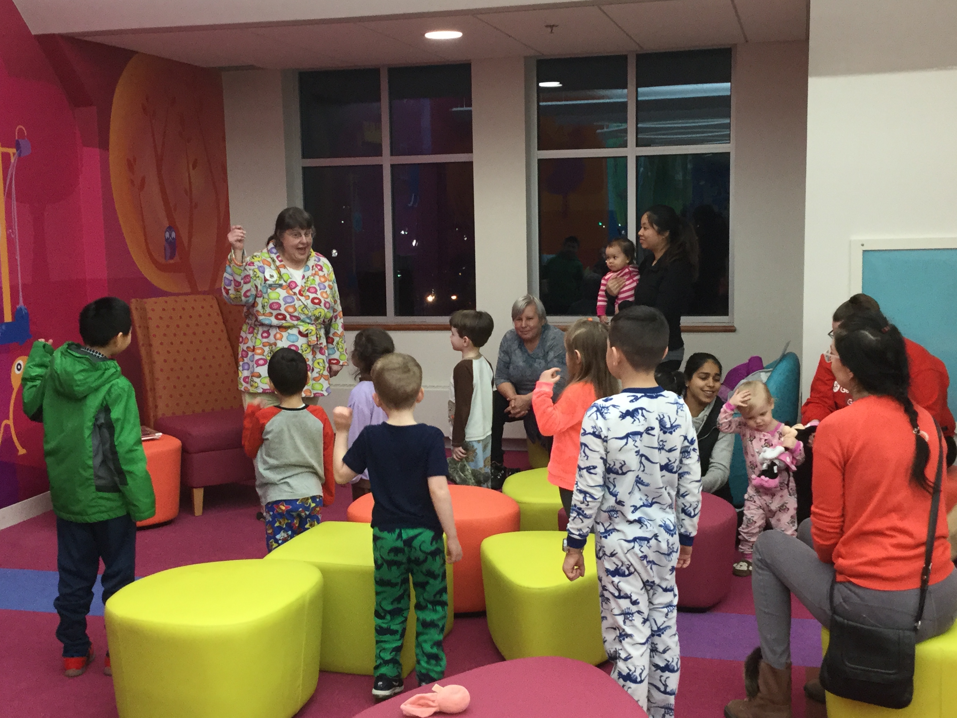 Families in Children's Room with Children's Librarian, some children in pajamas