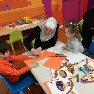 Guest reader for storytime wearing headscarf helping children with craft