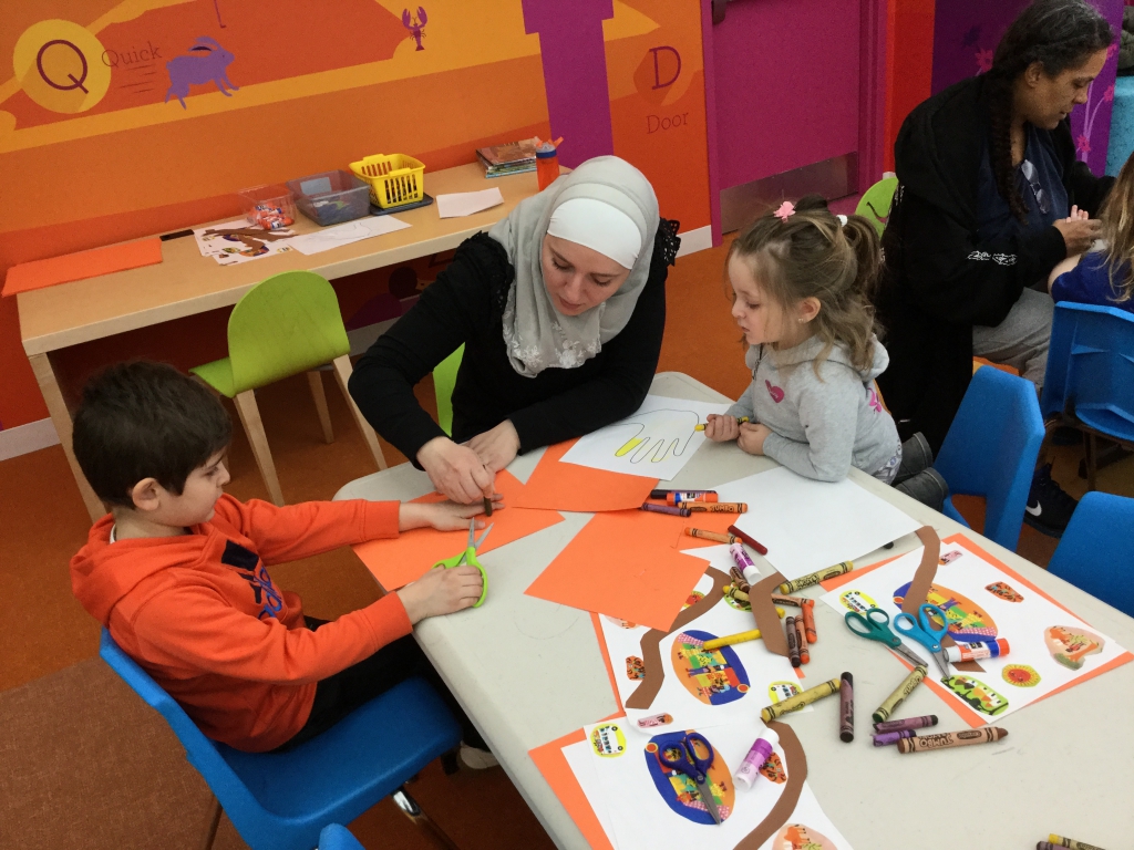 Multicultural Storytime Craft Guest reader for storytime wearing headscarf helping children with craft