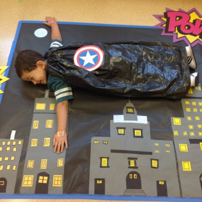 Young boy pretending to fly over buildings on floor mat