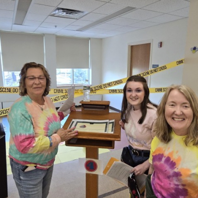 Three adults of mixed ages dressed in tie-dyed shirts