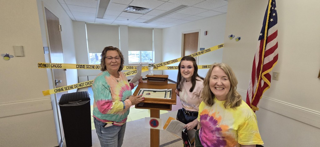 A team inspecting documents Three adults of mixed ages dressed in tie-dyed shirts