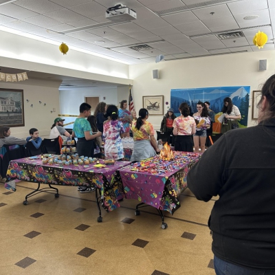 Tables covered with cupcakes and people gathered around not looking at refreshments