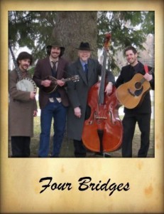 Picture of band -- four white men of various ages holding musical instruments outside under a tree